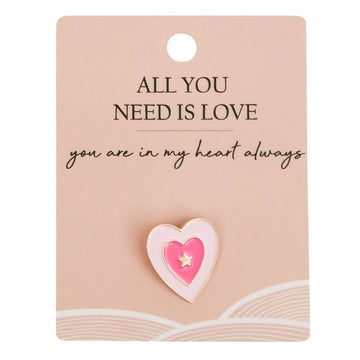 A heart shaped pin attached to a card with the heading 'All you need is love'.