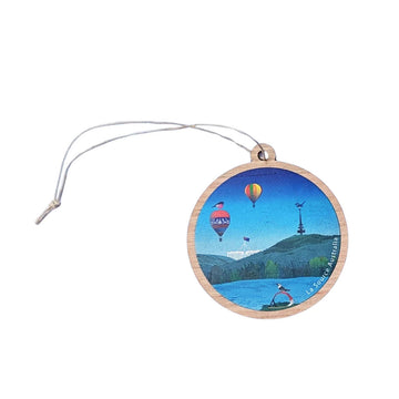A round wooden ornament illustrated with Canberra icons including hot air balloons, Parliament House and Telstra Tower.