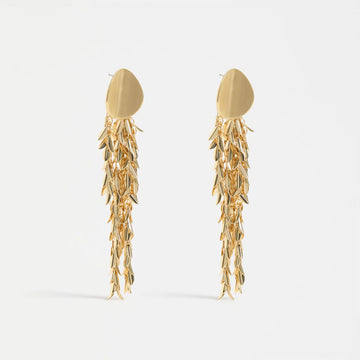 Gold leaf-like earrings on a white background.