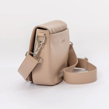 Front view of a saddle shaped light pink cross body bag.