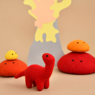 A red brontosaurus dinosaur standing next to piles of red and orange felt rocks.