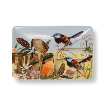A ceramic trinket tray with a painting of birds on a fence and flowers.