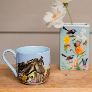 A ceramic mug illustrated with birds on a fence and flowers.