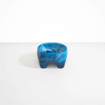 A small resin bowl with four legs in blue.