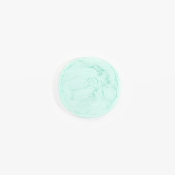 An irregular circle shaped resin coaster in mint green.