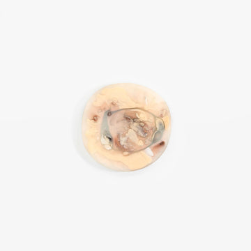 An irregular shaped round resin coaster in light beige brown.