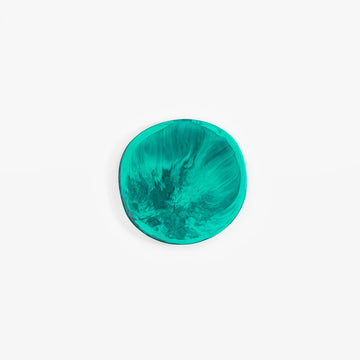 A irregular shaped round coaster in teal green resin.