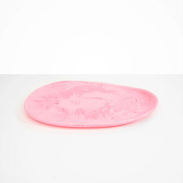 A irregular shaped round platter made from pink resin.