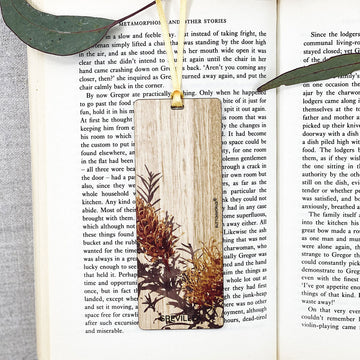 A wooden bookmark printed with grevillea flowers is inside a book.