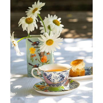 A ceramic tea cup and saucer printed with a kintsugi-style design with illustrations of flowers, birds and motifs.