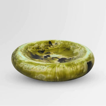 A round dish made from resin with dark green swirls.