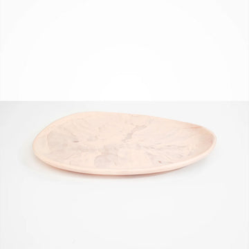 An irregular shaped oval platter in light pink resin.