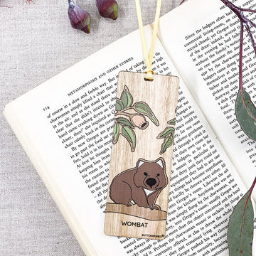 A wooden bookmark illustrated with a wombat is inside a book.
