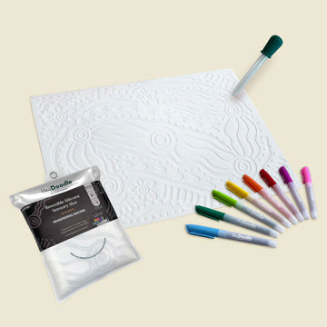 White embossing mat with a pen and colorful markers on a beige background.