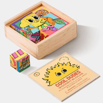 A hand is holding a wooden cube printed with different pictures next to an almost completed puzzle made from wooden cubes.