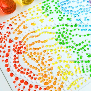 White embossing mat with a pen and colorful markers on a beige background.