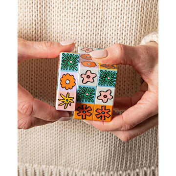 A rubik's style cube with different illustrated flowers on each square.