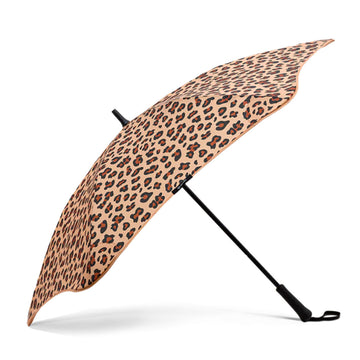 An open umbrella printed with leopard print resting on its black handle.