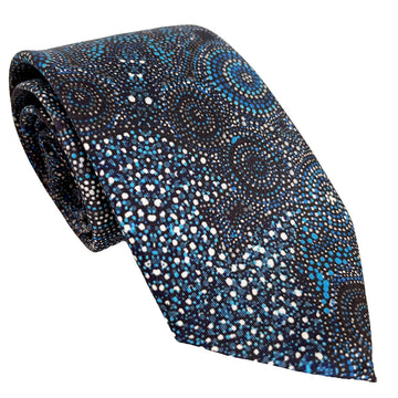 A tie printed with Indigenous artwork in blue and black is rolled up.
