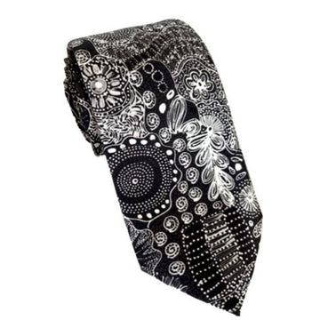 A tie printed with Indigenous artwork in black and white is rolled up.