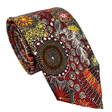 A tie printed with Indigenous artwork in reds, browns and white is rolled up.
