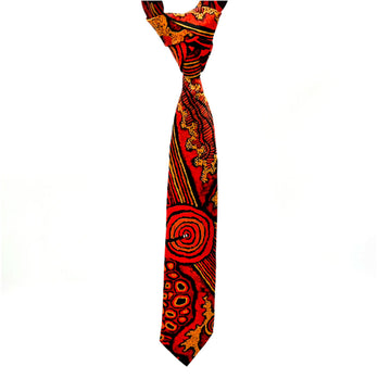 A tie is hanging down and printed with artwork by Damien and Yilpi Marks in red, orange and brown.