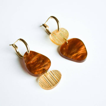 A pair of gold hoop earrings with two irregular shaped round shapes linked together in shades of brown.