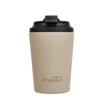 A reusable coffee cup in a light oat brown with a black lid and the text 'made by Fressko' on the bottom.