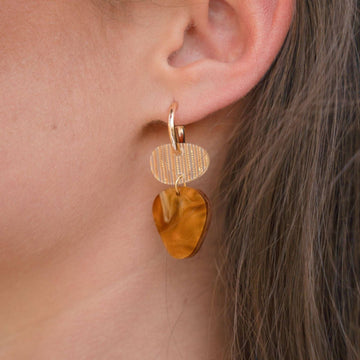A pair of gold hoop earrings with two irregular shaped round shapes linked together in shades of brown.