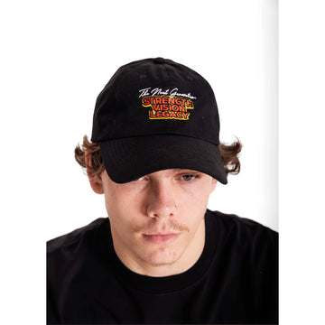 Close up front view of a man wearing a black cap with the text 'The Next Generation Strength Vision Legacy'.