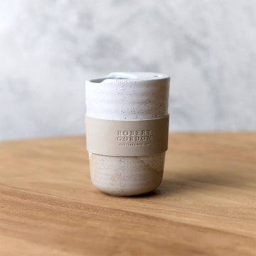 A ceramic travel mug with a silicone sleeve and a speckled design.
