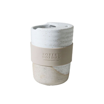 A ceramic travel mug with a silicone sleeve and a speckled design.