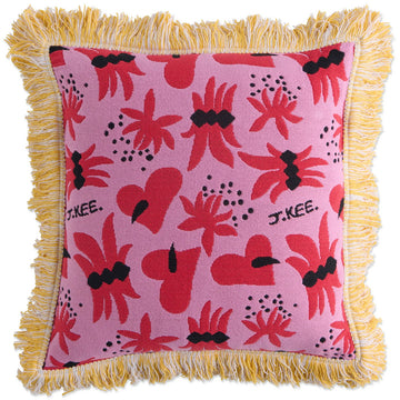 Front view of a woven cushion printed with red floral and heart motifs with a yellow tassel edge.