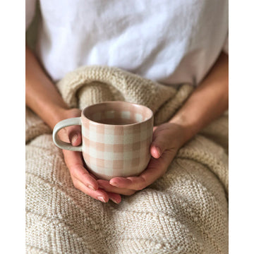 A ceramic mug printed with a pink checkered pattern.