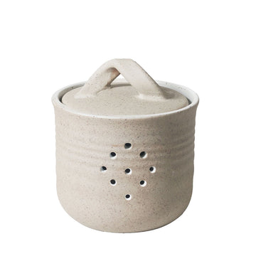 A ceramic container with a lid and holes on the front.