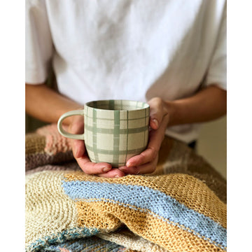 Green plaid patterned mug on a white background.