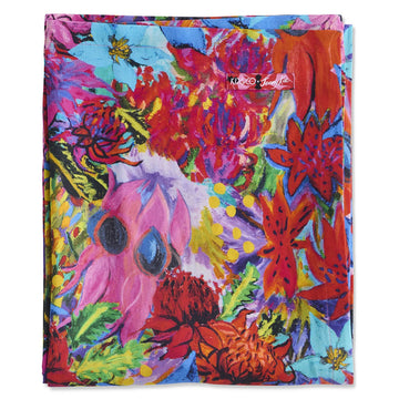 A folded up fabric table cloth printed with colourful floral artwork.