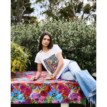 A folded up table cloth printed with colourful abstract artwork of flowers.