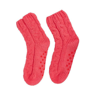 A pair of cable knit socks in a melon pink colour with small round grip pieces on the sole.