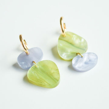 A pair of gold hoop earrings with two irregular shaped round shapes linked together in shades of green and blue.