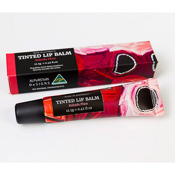 A tube of lip balm with pink artwork next to its matching box.
