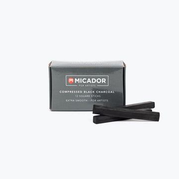 A small black box with the heading 'Compressed Black Charcoal' and three sticks of charcoal in front of the box.