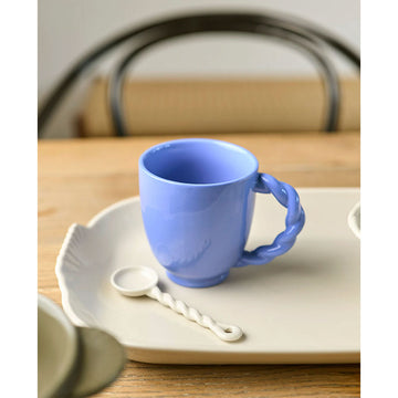 Blue mug with a twisted handle on a white background.