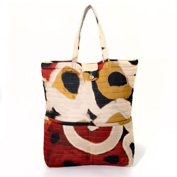A quilted style tote baby bag printed with a cream, black, red and mustard print.