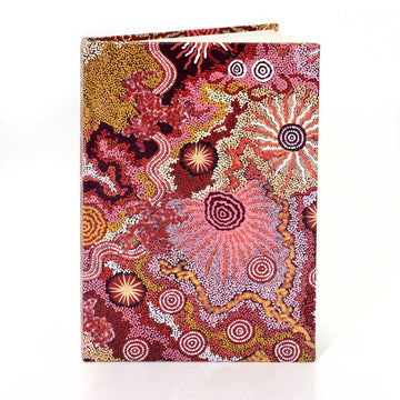 A hard cover notebook printed with Indigenous artwork in shades of red and yellow on the front.