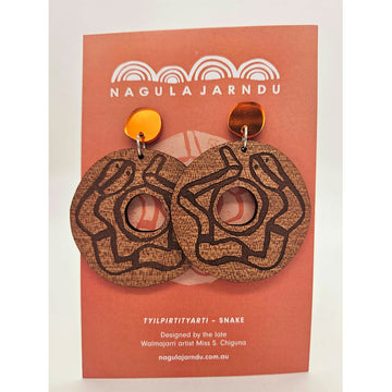 Blue round drop earrings with an etching of a snake on a 'Nagula Jarndu' branded card.