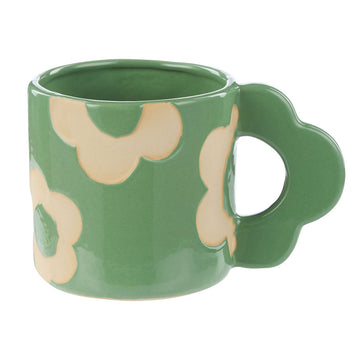 A ceramic mug in green with a flower shaped handle and light yellow flowers on the mug.