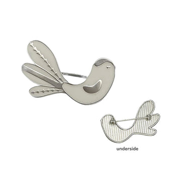A silver bird brooch with a second brooch showing the pin on the underside.