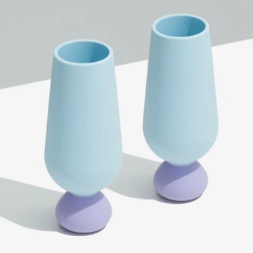 Two light blue and purple champagne glasses on a white surface with a gray background.