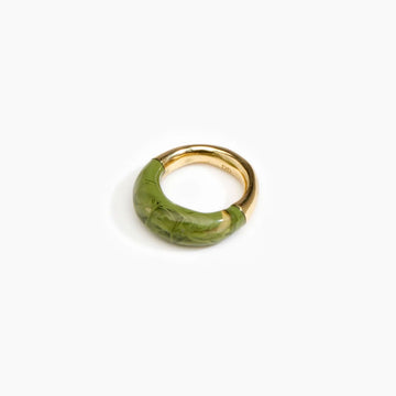 A brass ring half covered with olive green resin.